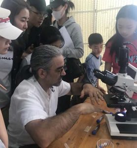 Thomas explaining observation of soil microbiota with a microscope